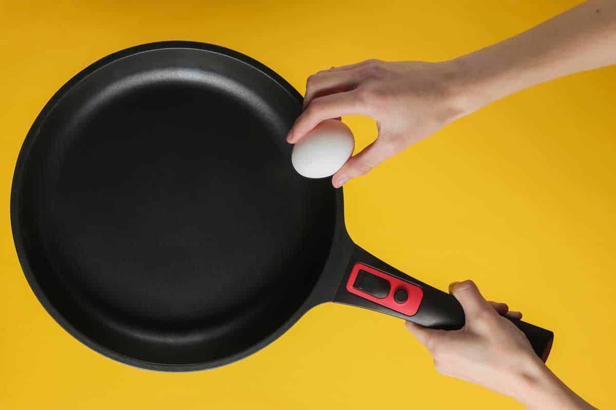 女性的手把鸡蛋吐在有不粘锅涂层的煎锅上。什么时候应该扔掉不粘锅?