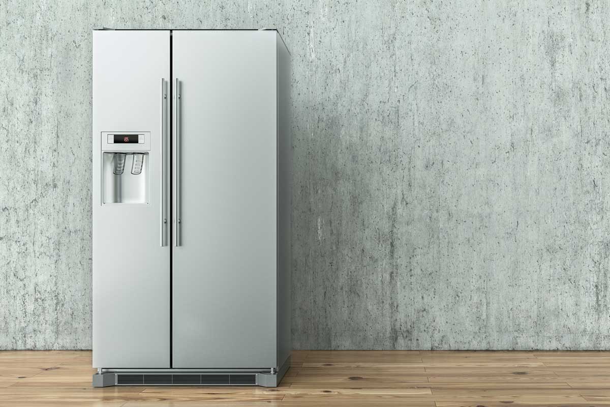 现代不锈钢冰箱在混凝土墙上和木地板上，市场上最好的冰箱品牌＂width=