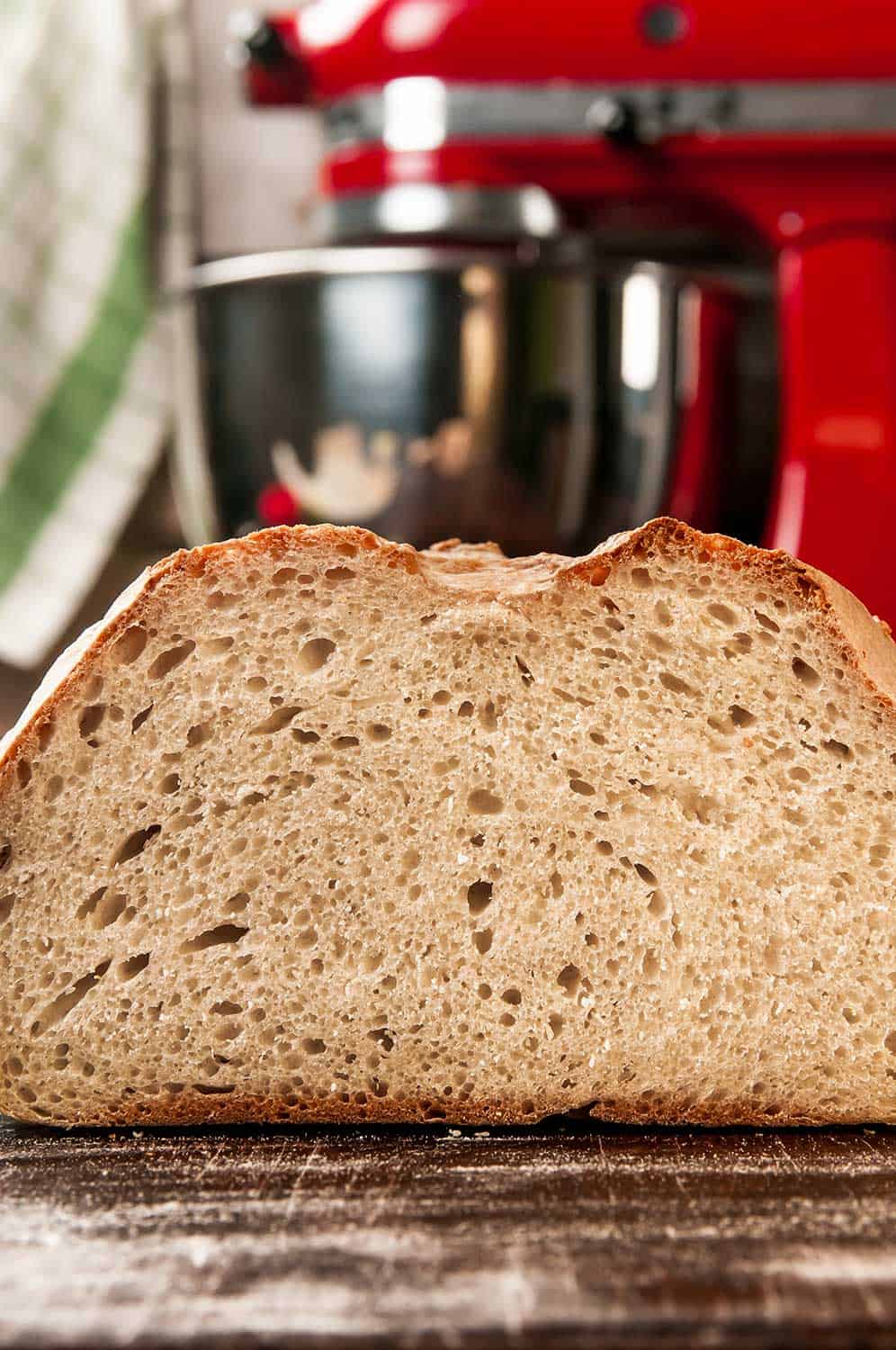 自制面包的横截面放在撒了面粉的表面，背景是搅拌器