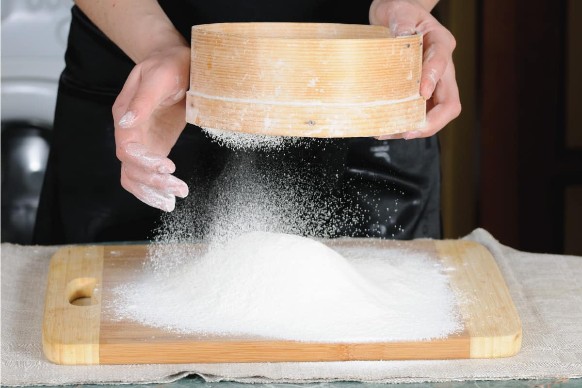 用筛子将白面粉筛到切菜板上，筛子可以用洗碗机清洗吗?下面是如何清洗筛子的方法”width=