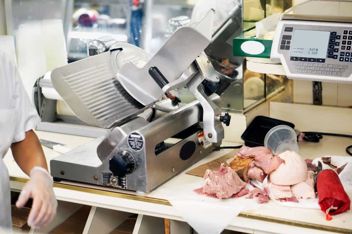 肉店柜台上放着冷盘，旁边是肉片机，你能用食品加工机切肉吗?