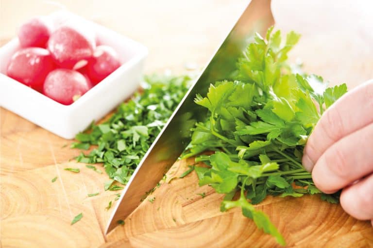Chopping-fresh-parsley-using-chef 's-knife-on-a-chopping-board。厨师刀有多长，厨师刀有多长?