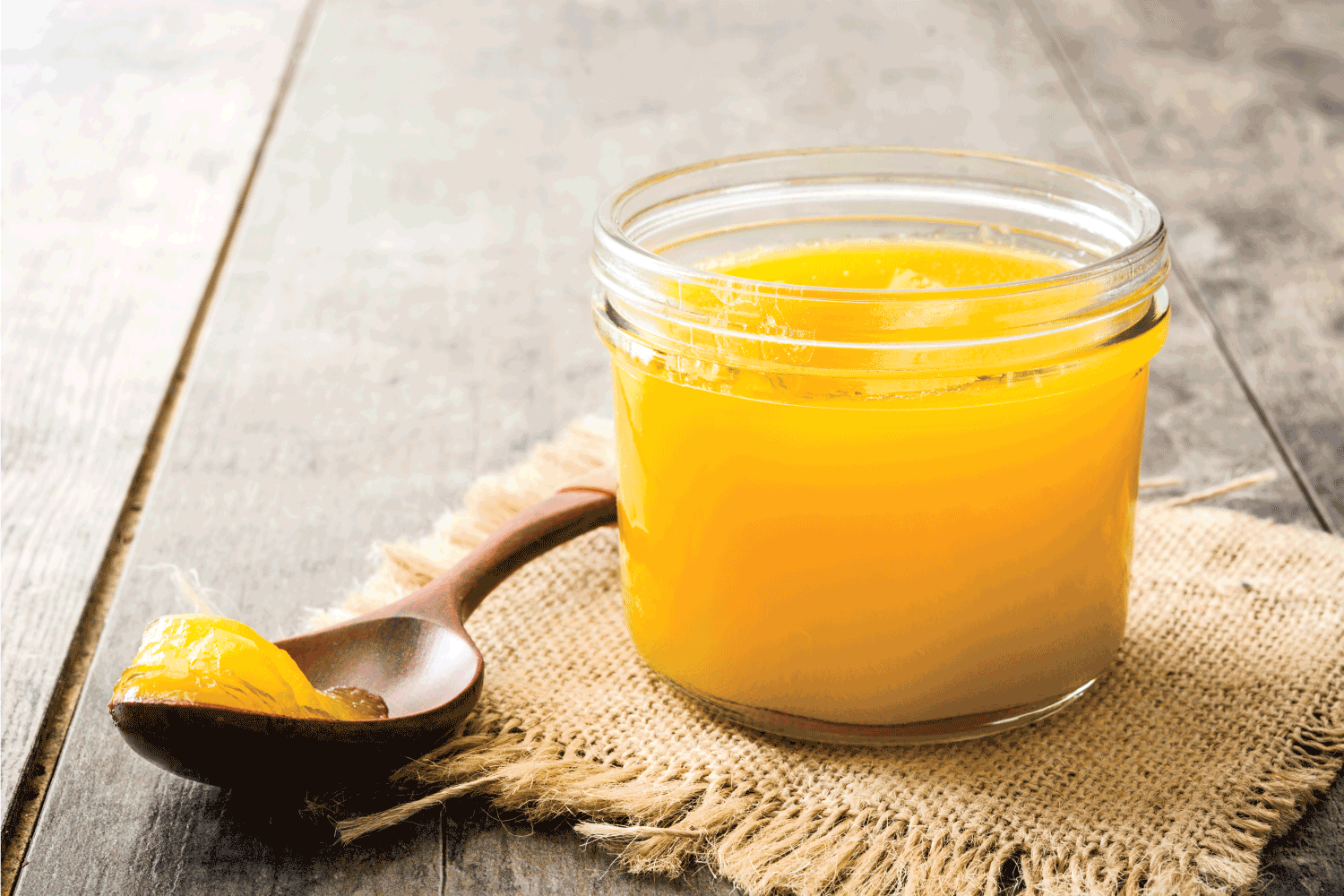 酥油或澄清黄油在罐子和木勺在木桌上