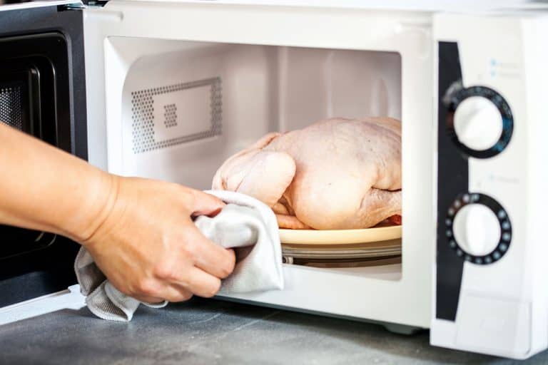 一个女人用微波炉加热整个微波熟鸡肉,鸡肉放进微波炉里使其橡胶吗?