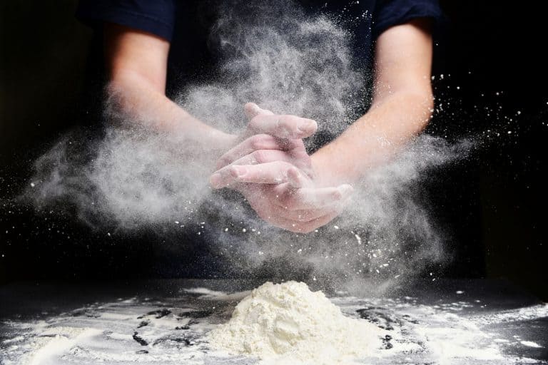 厨师用面粉拍打双手。面粉的白尘，面粉品牌对烘焙有影响吗?