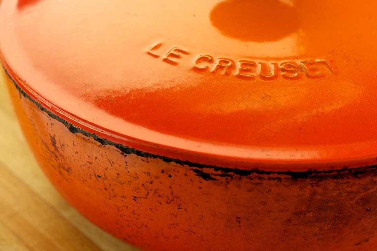 经典的橙色乐Creuset珐琅涂层铸铁烹饪锅苦恼的痕迹