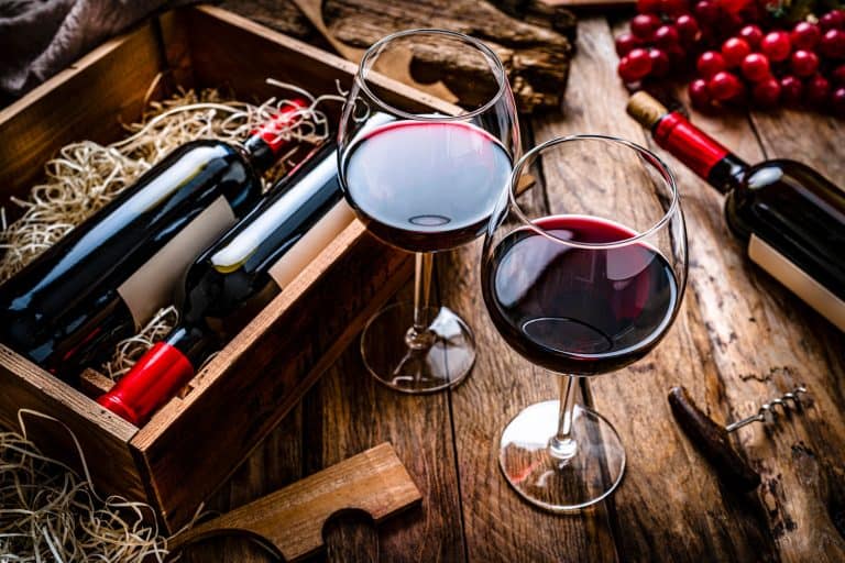 在乡村木桌上拍摄的两个红色酒杯，高角度视角，昂贵的酒杯值得投资吗?