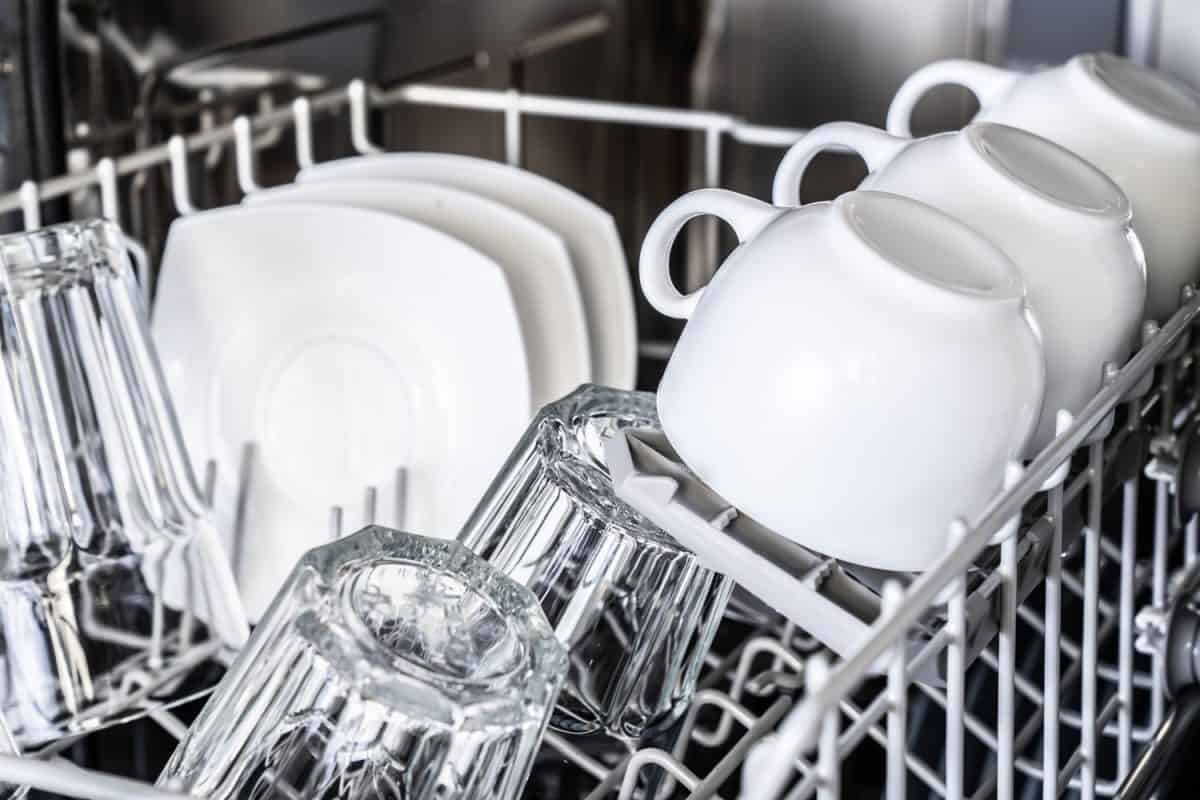 新洗碗机中的白色杯子特写。干净的盘子。管家设备。