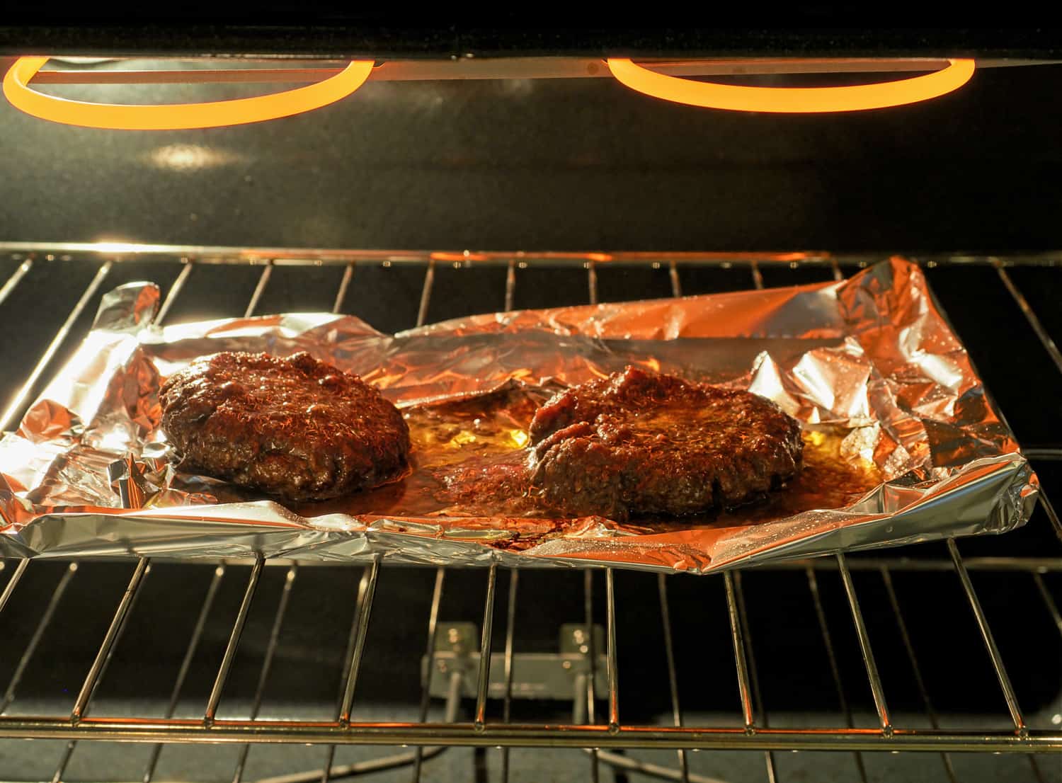 油腻的汉堡包在电炉里烤着。将汉堡肉饼放在铝箔托盘上，以收集大量不健康的油脂。