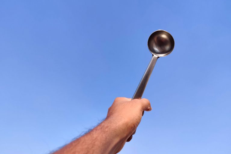 手拿着银laddle的男人。一种勺用于汤、炖肉、或其他食物,一个包多少钱?(大小探索)