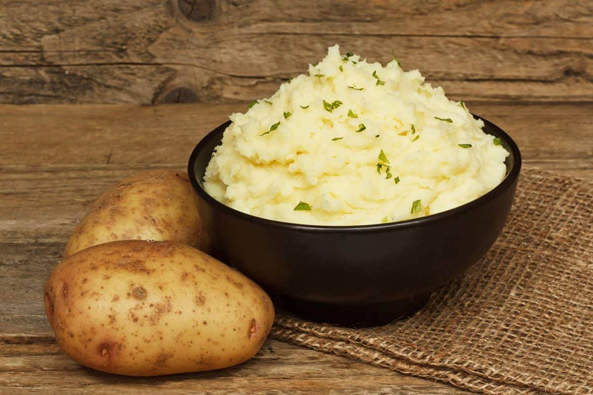 由煮熟的土豆和黄油混合而成的奶油土豆泥，在传统的乡村背景上，放在一个黑色的碗里