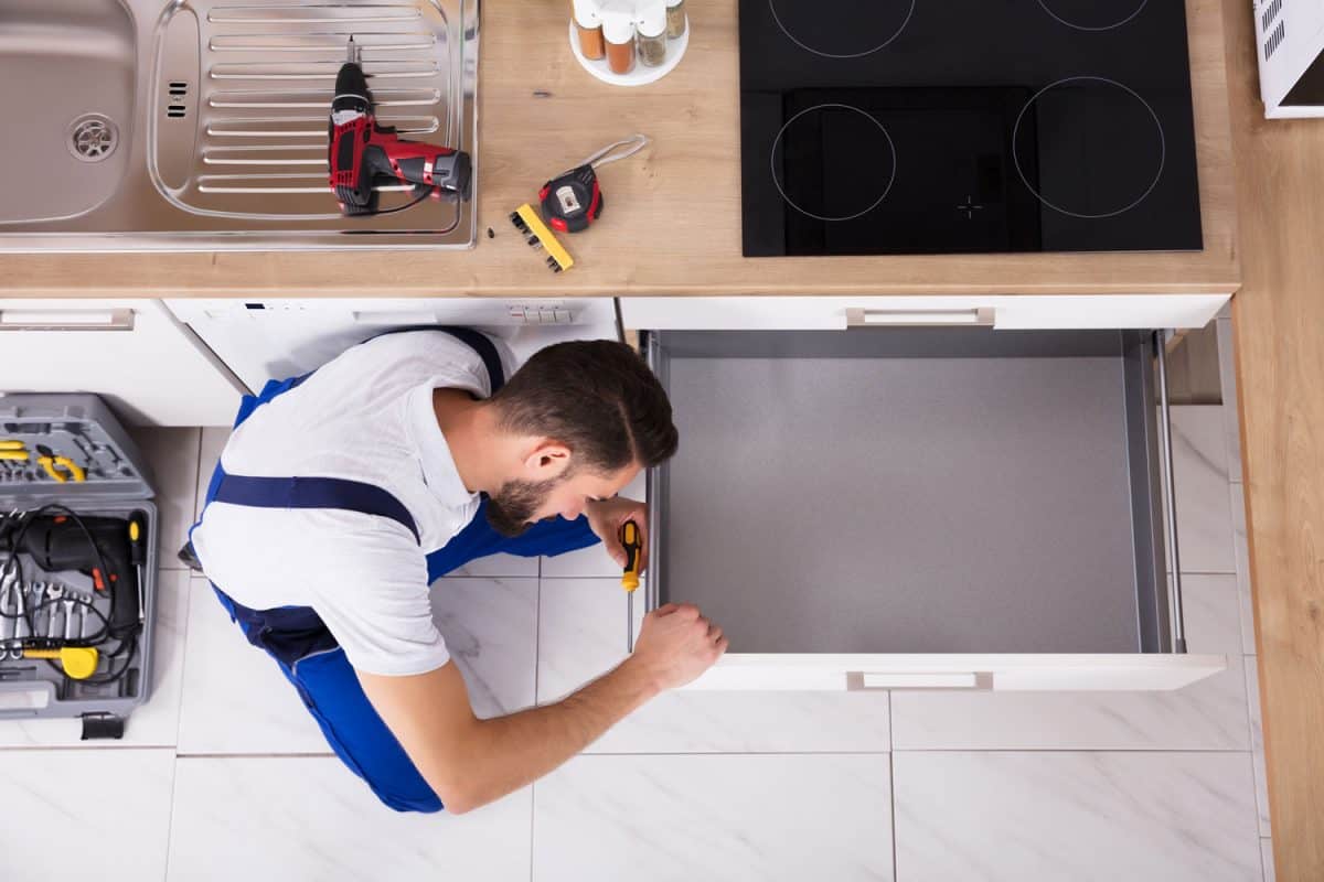 高角度视图的男性木匠修理厨房抽屉里,你可以购买更换厨房抽屉吗?bd手机下载