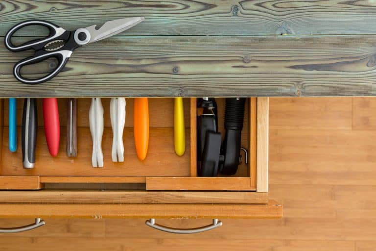 用一把剪刀或剪刀从头顶往下看，厨房的抽屉里放着整齐的彩色刀具，上面有一个质朴的台面。bd手机下载