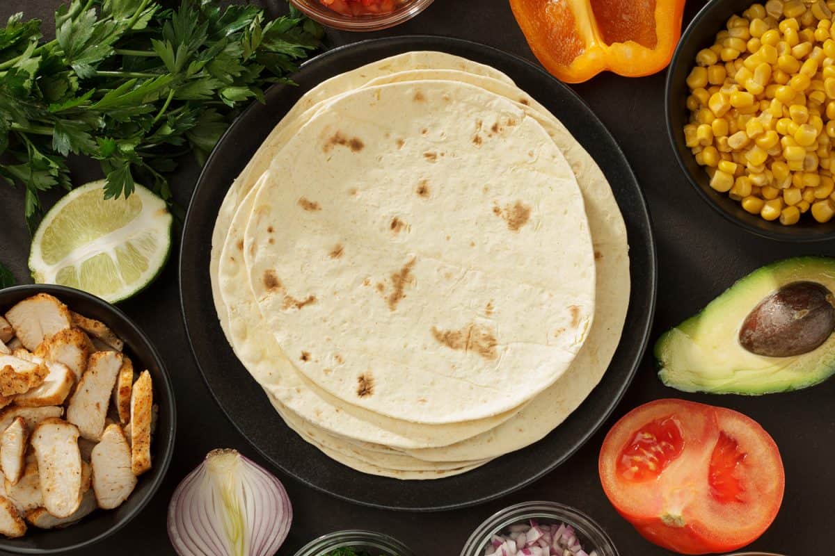 墨西哥玉米卷的配料背景是大饼、新鲜蔬菜和烤鸡肉。墨西哥快餐顶部视图与复制空间。