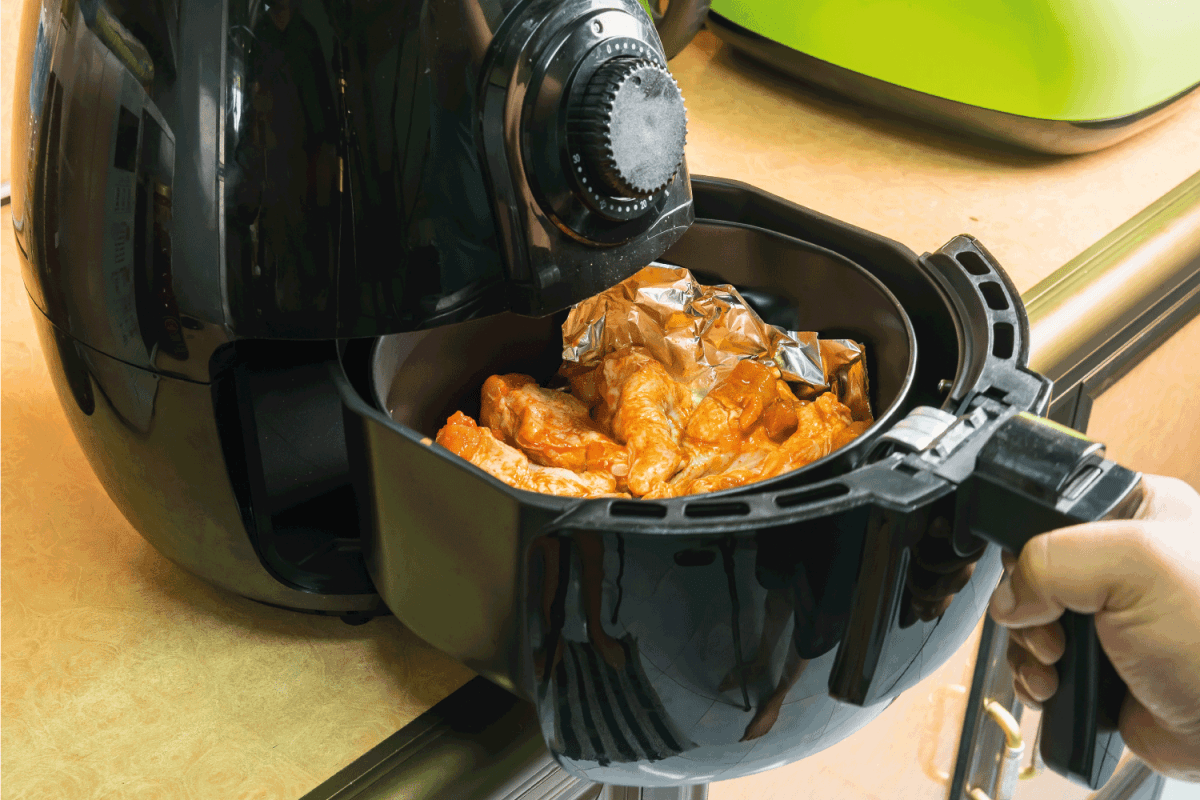 厨师烧烤鸡腿在烤箱空气炸锅与铝箔。无油健康烹饪