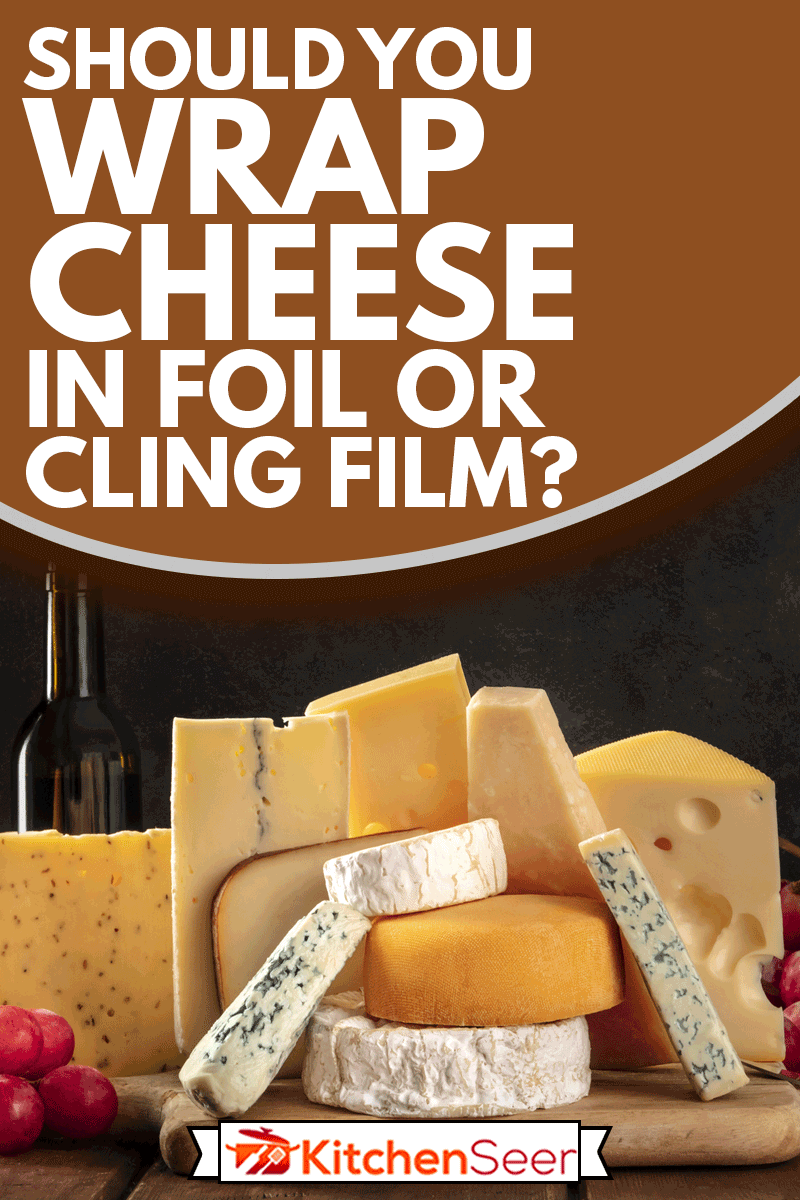 奶酪与葡萄和倒酒，侧视图在一个黑暗的背景与复制空间，你应该用箔纸或保鲜膜包裹奶酪?