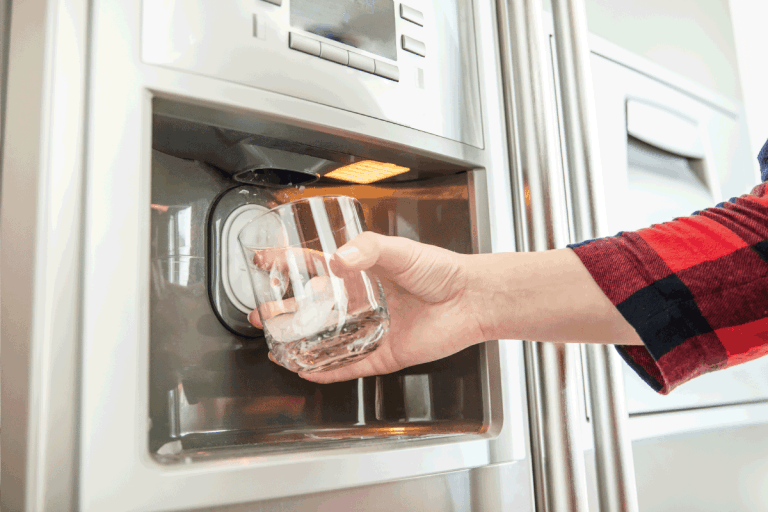 女人的手是玻璃和使用冰箱让新鲜干净的冰块。解冻三星制冰机多久
