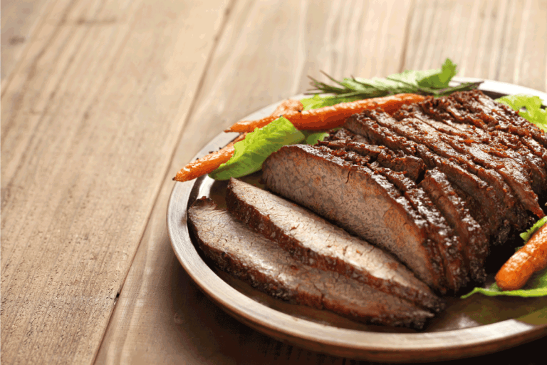 烧烤牛肉胸肉在一个白盘子,木桌子。在什么温度下你应该煮烤