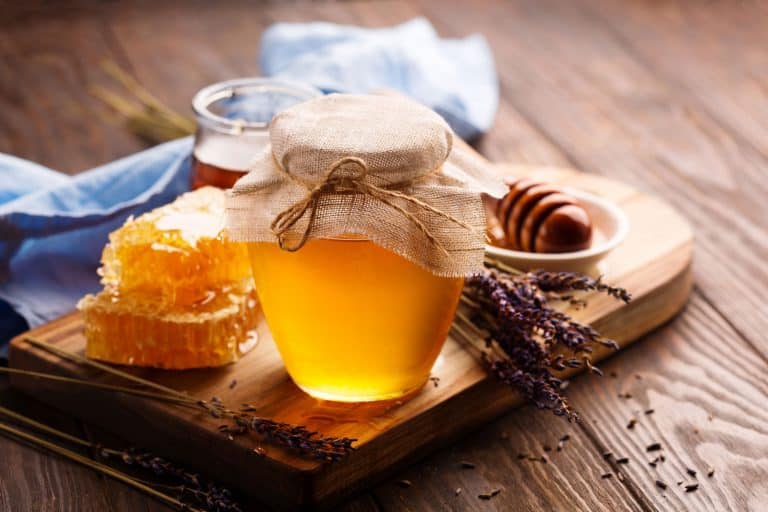罐液体蜂蜜,蜂巢内部和一些干薰衣草在旧的木桌上,最好的容器来存储是什么亲爱的?