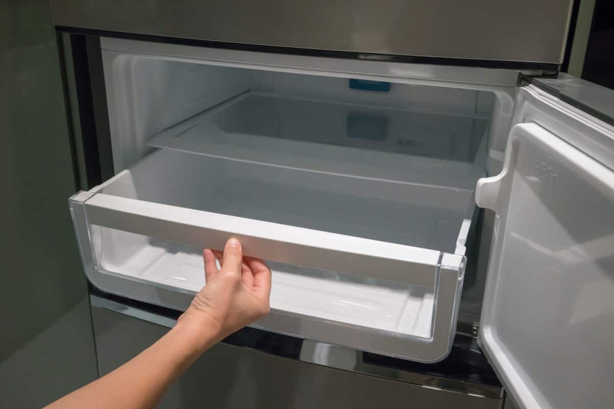 一个女人打开冰箱抽屉清理