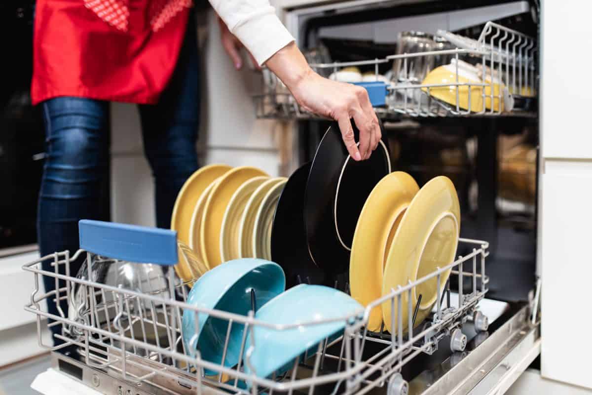 一个女人把盘子放进洗碗机里洗