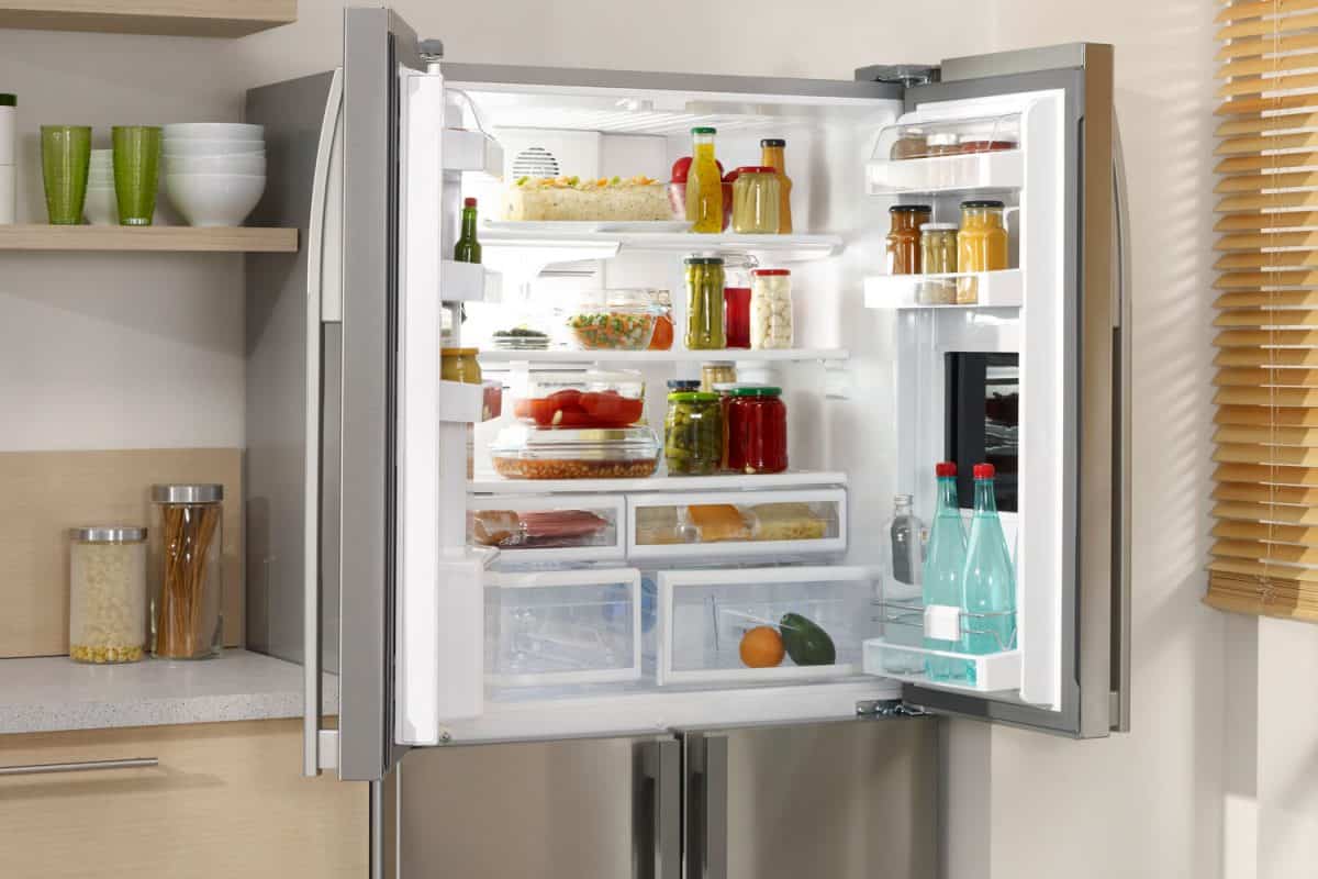一个打开的双门冰箱，里面有很多烹饪必需品