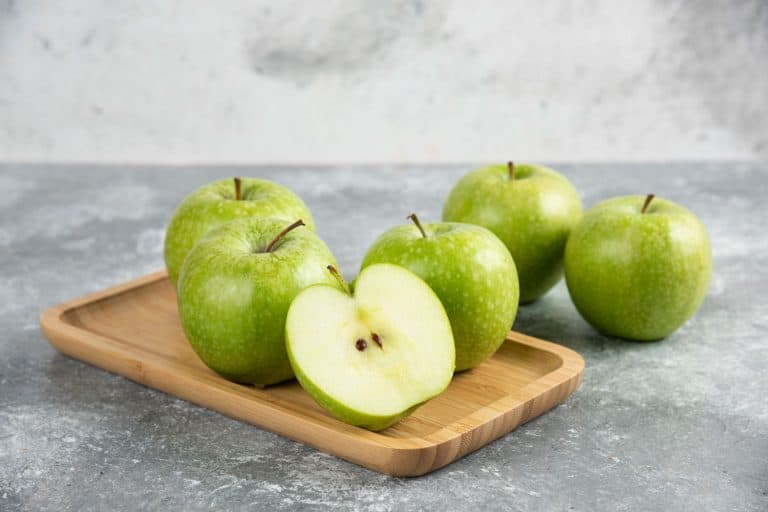 一串完整的切成片的青苹果放在木盘上。《如何冷冻青苹果》