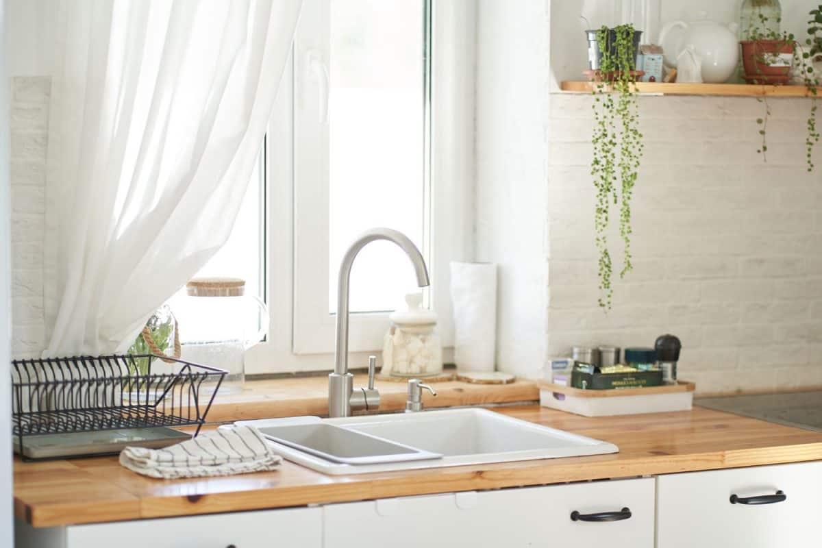 这是一间斯堪的纳维亚主题的厨房，有木质台面、bd手机下载白色简约风格的水槽和一扇巨大的白色框窗，