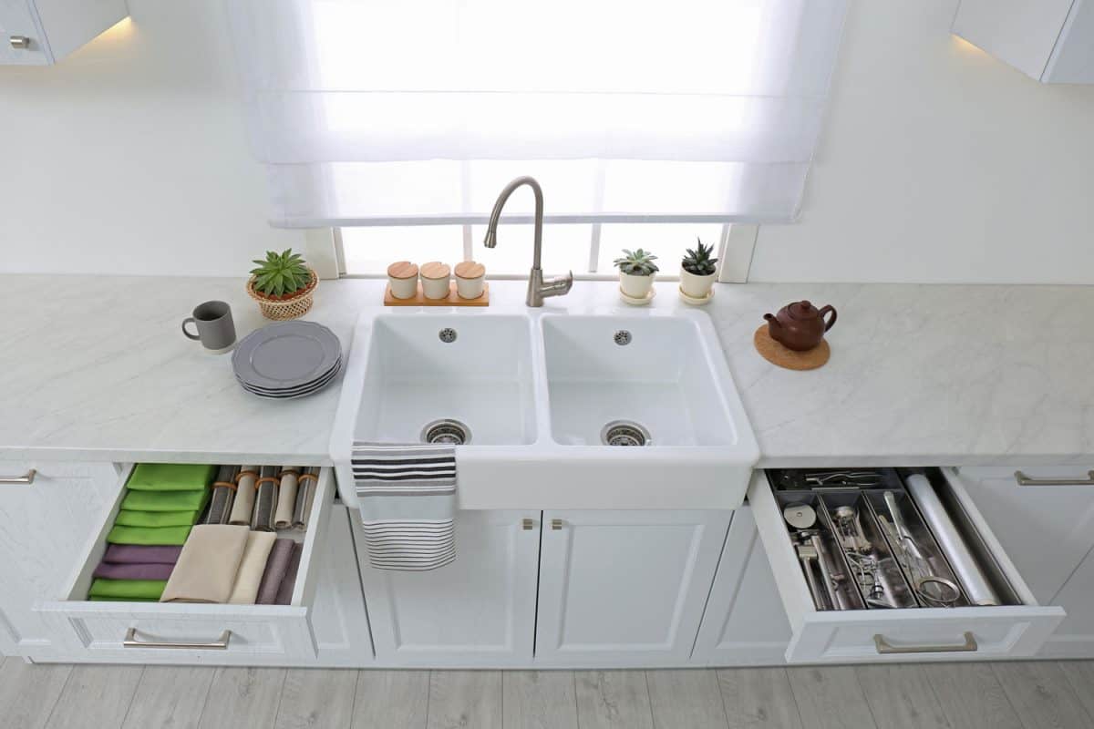 白色主题的厨房台面、白色水槽、bd手机下载打开的抽屉和靠近窗户的小多肉植物