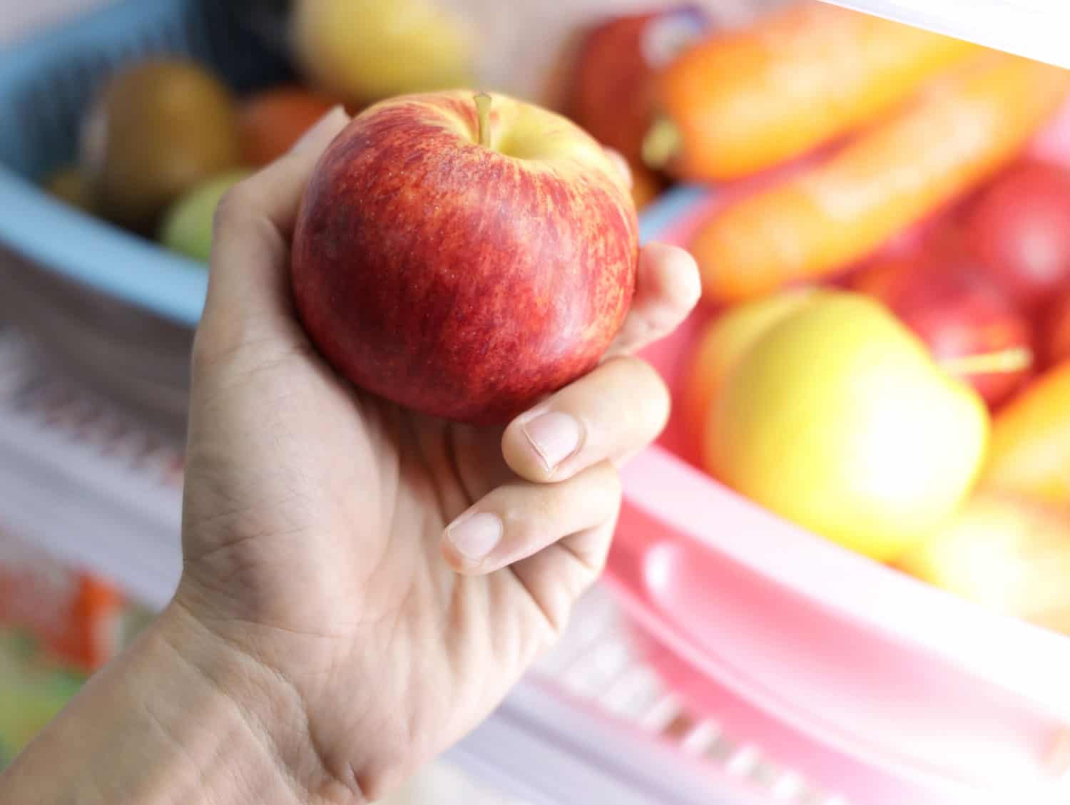 近距离的女人手拿红苹果在厨房的冰箱bd手机下载