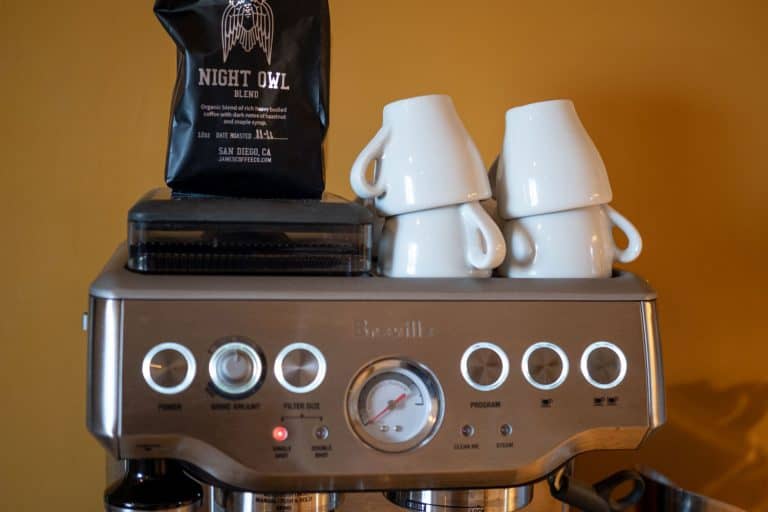 杯子和一袋咖啡豆放在一个Breville咖啡机,如何重置Breville浓缩咖啡机