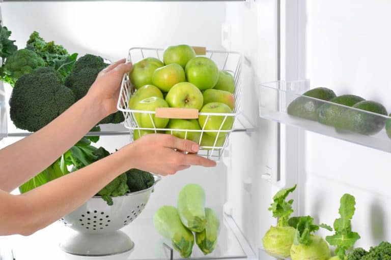 女性的手和篮子新鲜苹果在冰箱,冰箱里做苹果持续更长时间或在柜台上?