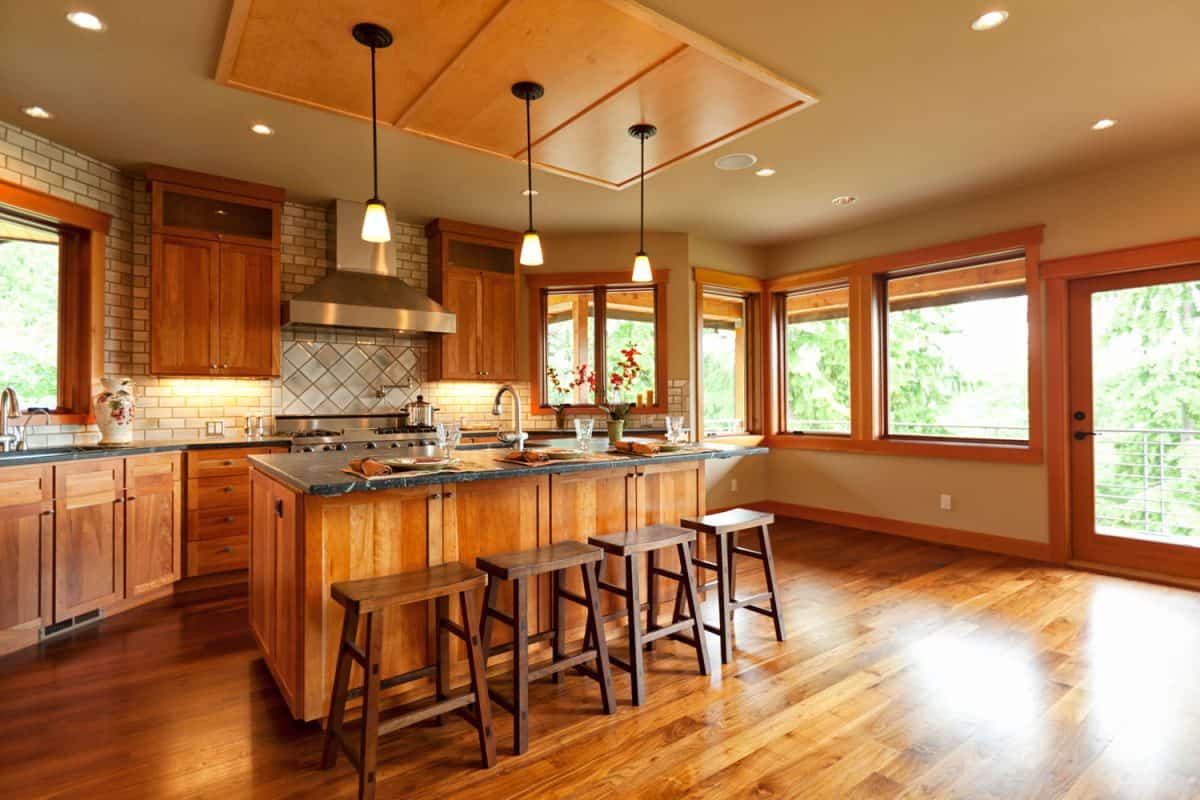 乡村主题厨房的内部，有木地板，木制早餐吧和巨大的木框窗户bd手机下载