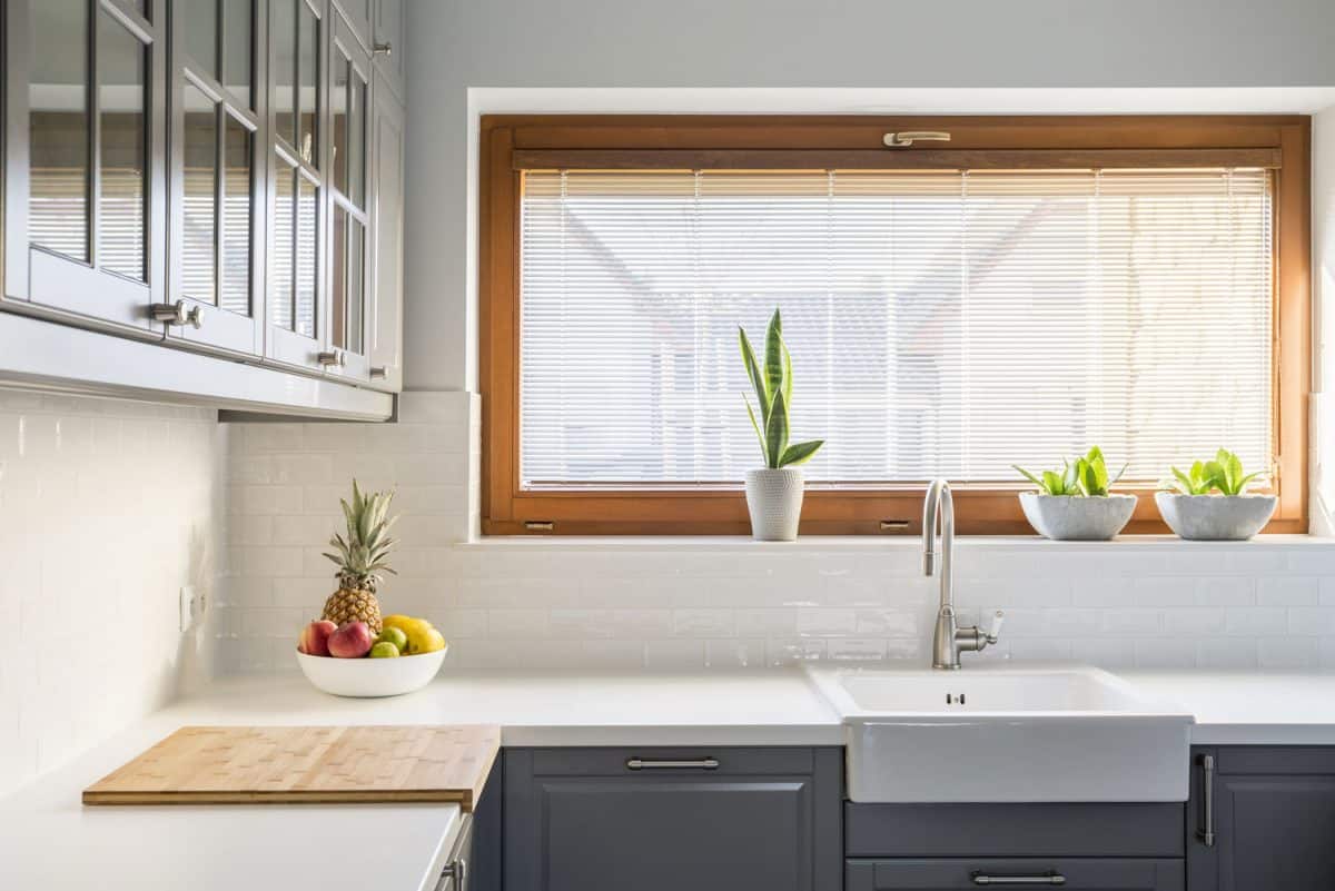 浅色厨房，白bd手机下载色台面，水槽，窗户和灰色家具