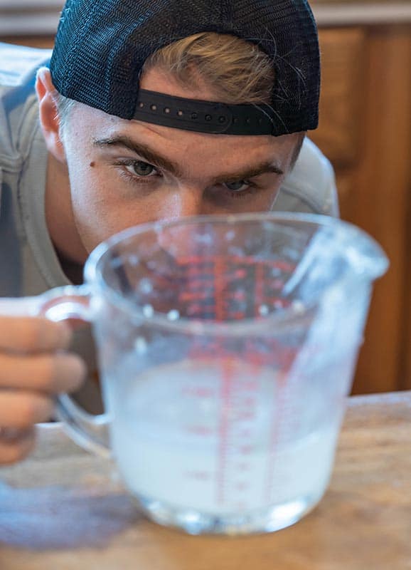 一个年轻人仔细测量水的成分，为家庭烘焙做准备