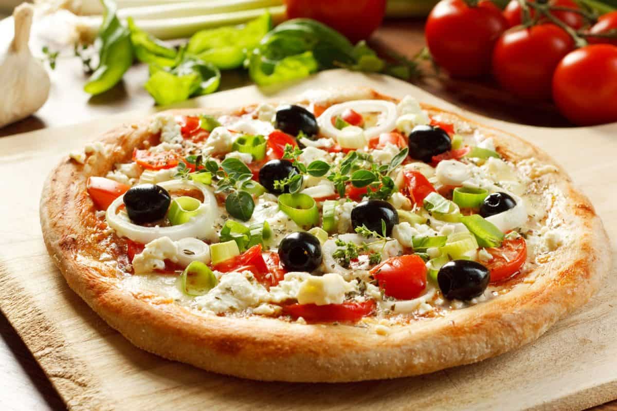 新鲜素食希腊风格披萨与橄榄，洋葱圈，羊乳酪，马苏里拉奶酪，西红柿和新鲜香草