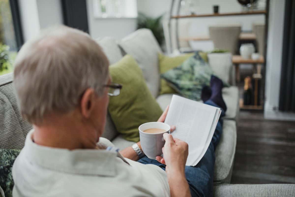 一个年长的男人一边阅读报纸一边享受着一杯咖啡