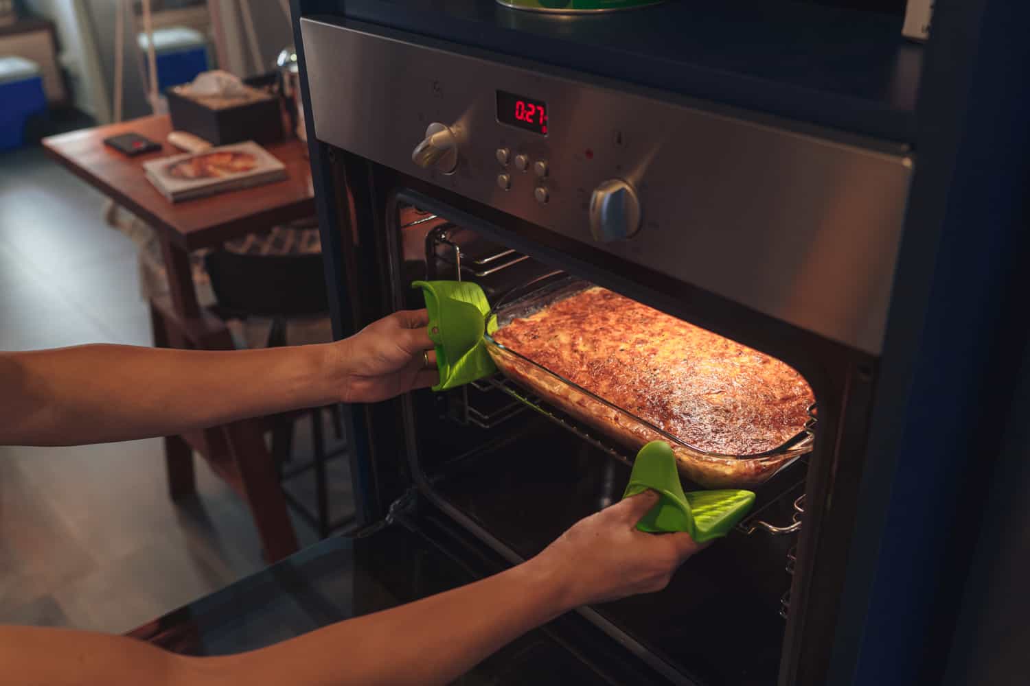 一双手从烤箱里取出刚烤好的千层面