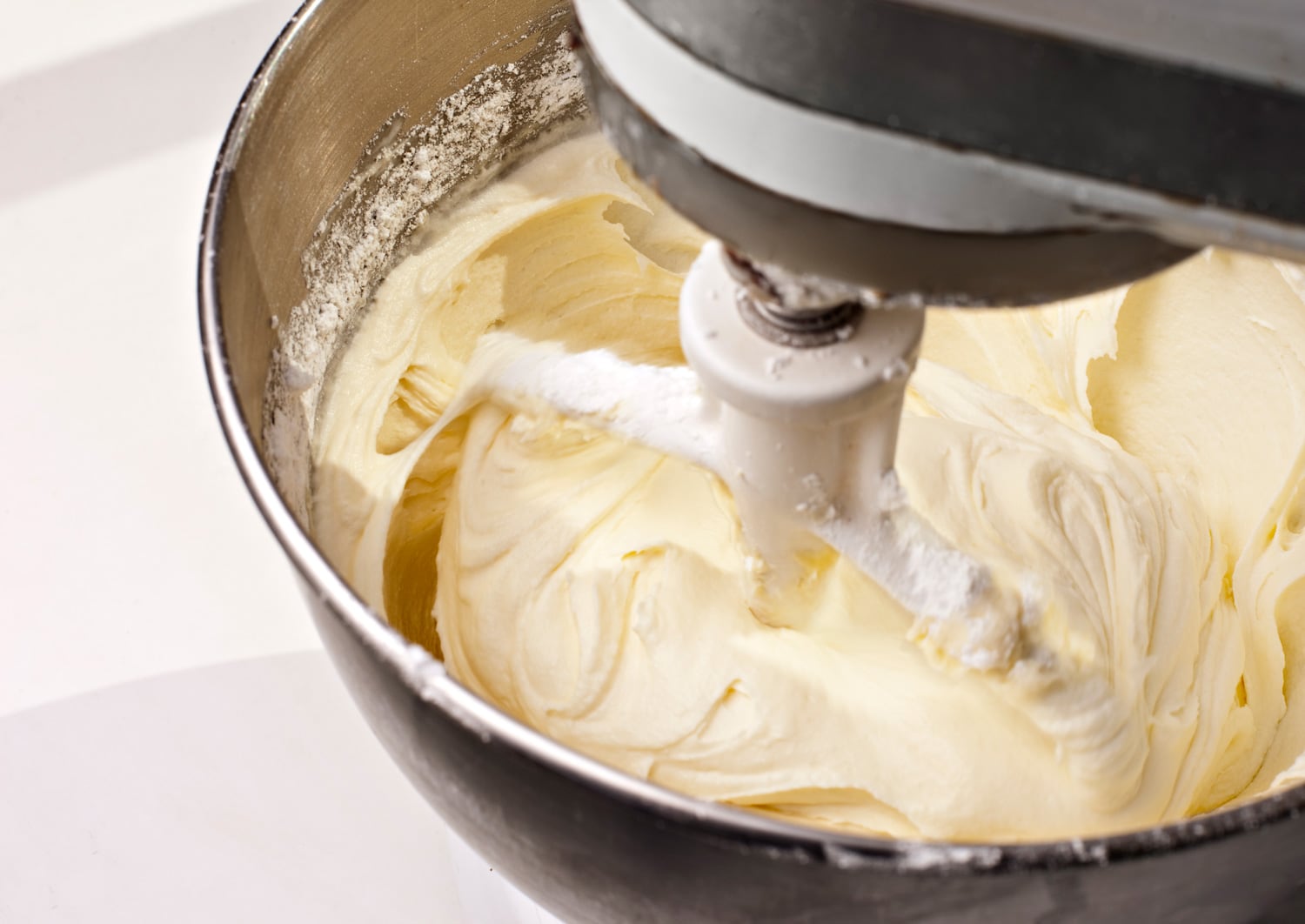 电动搅拌机混合黄柠檬奶油乳酪蛋糕糖霜。