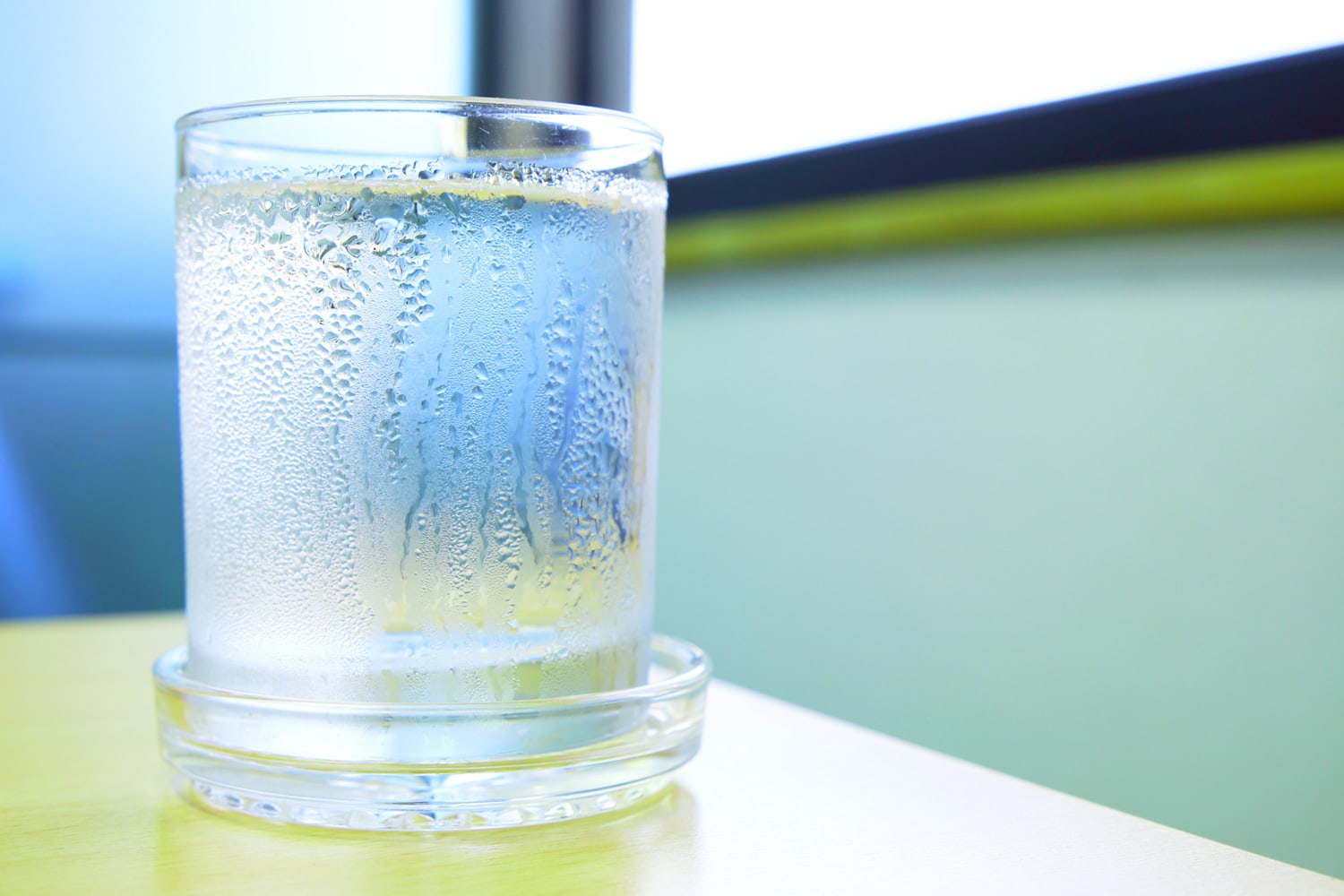 杯子里的水，水滴在靠近窗户的木桌上。