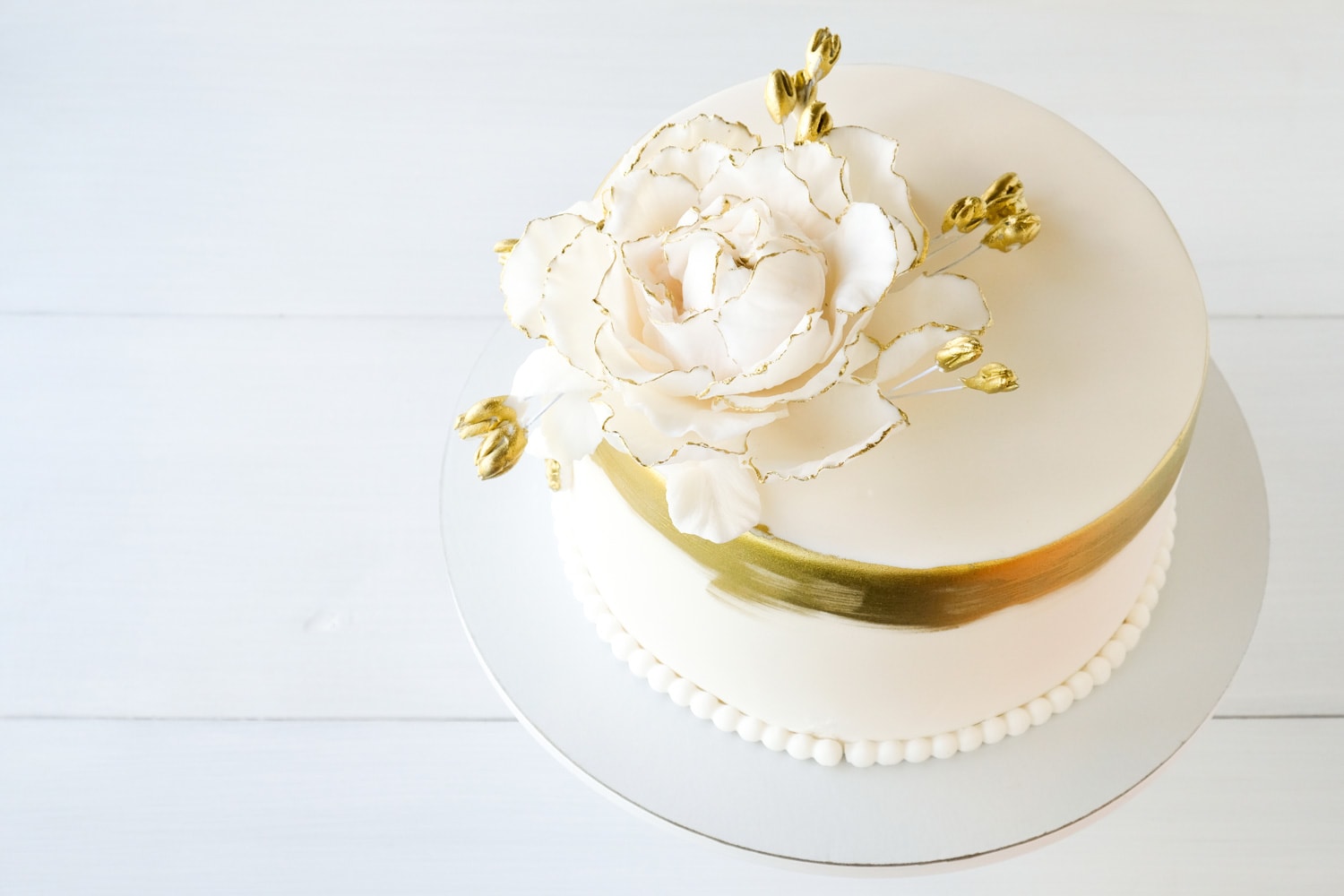 白色的婚礼蛋糕，白色的背景上装饰着金色的花朵。