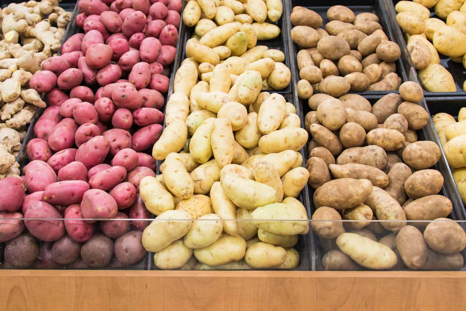 杂货店陈列着不同颜色和品种的土豆，供人们排队挑选他们最喜欢的农产品