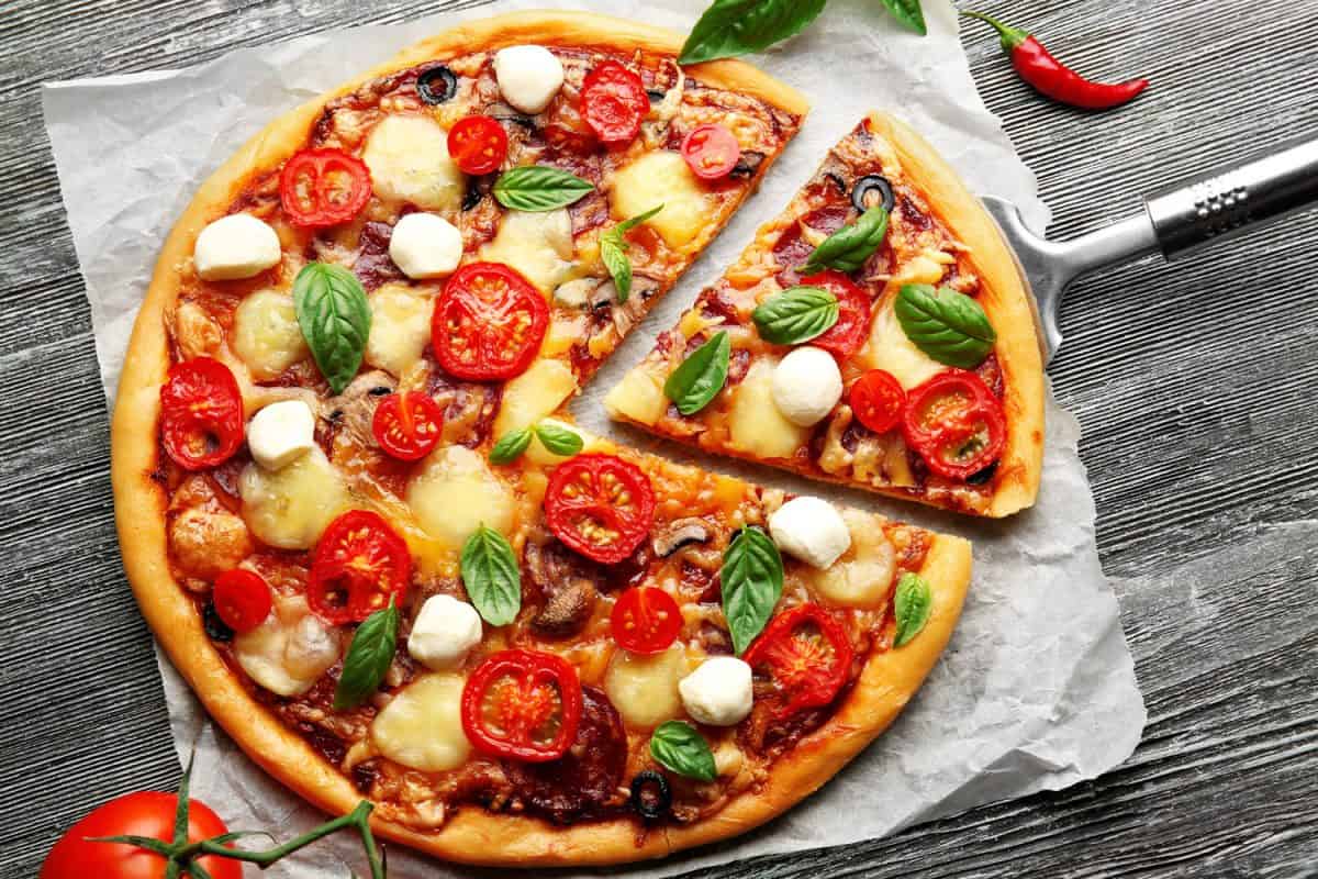 美味的披萨，奶酪，西红柿和鱿鱼球放在羊皮纸上