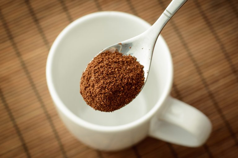 勺子与咖啡粉在白色的空杯棕竹背景。使12杯咖啡——咖啡粉多少钱