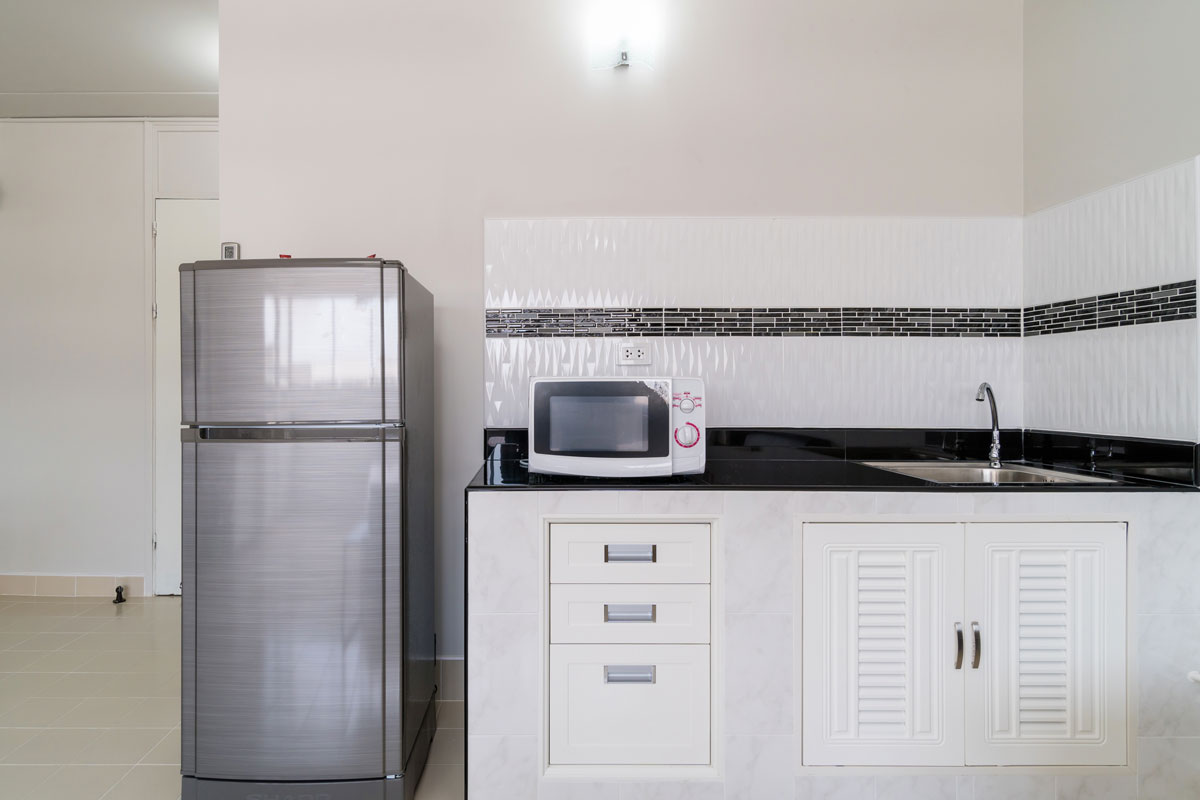 一间小公寓厨房，有白色橱柜和白色瓷砖bd手机下载挡板