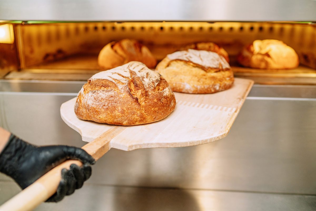 面包师把面包放进面包房的烤箱，蜷缩在面包房的地板上