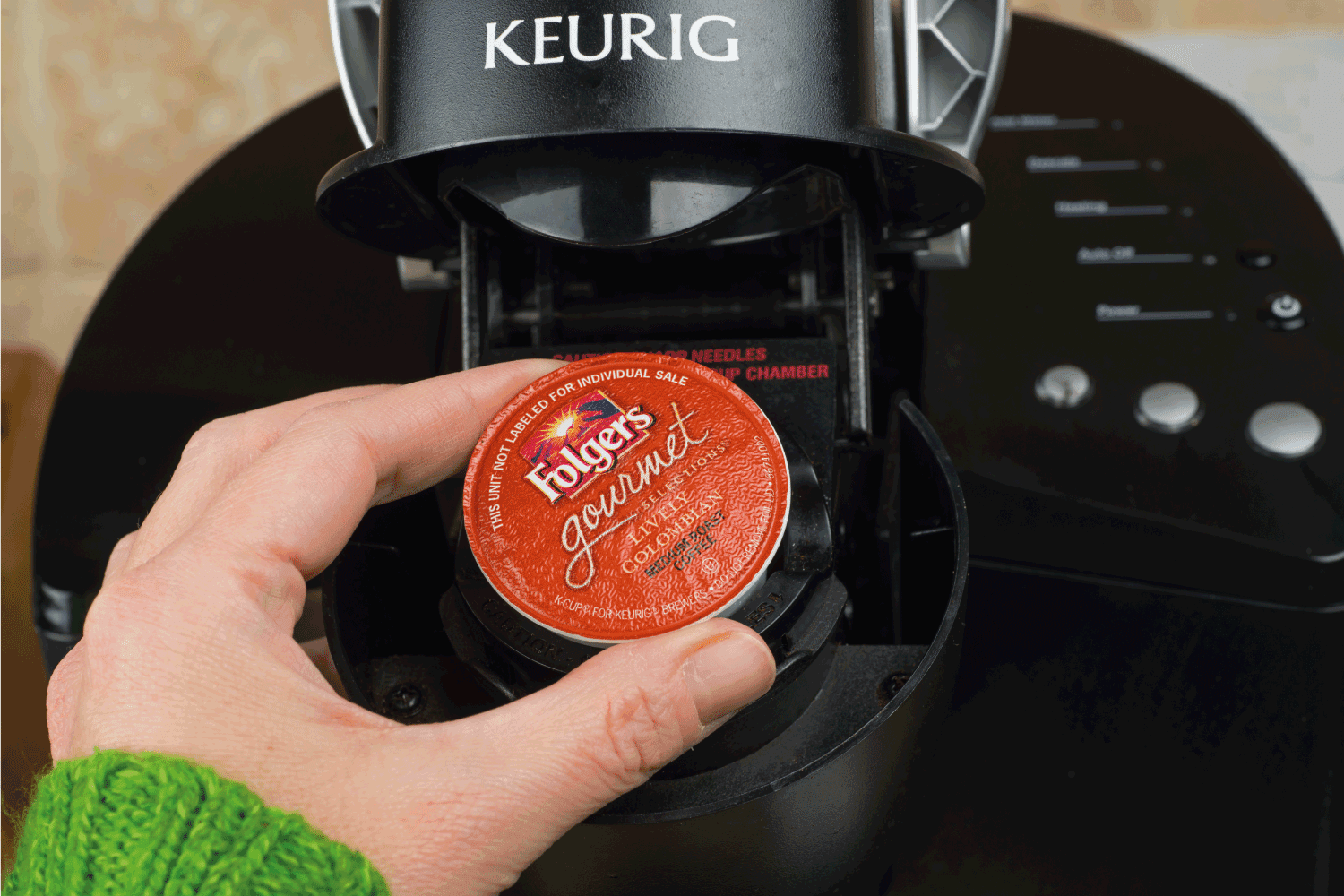 一名女子将单杯k杯Foldger咖啡插入Keurig咖啡机中。