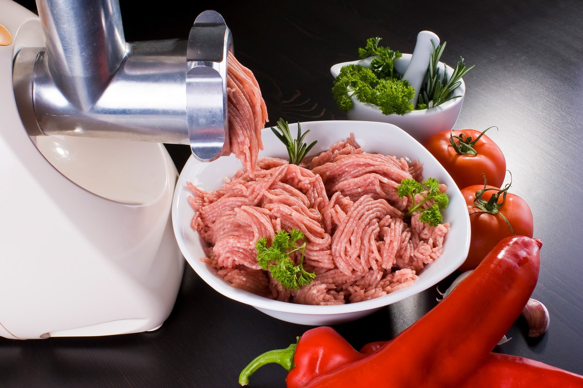 配有电动绞肉机和蔬菜的一碗肉糜。
