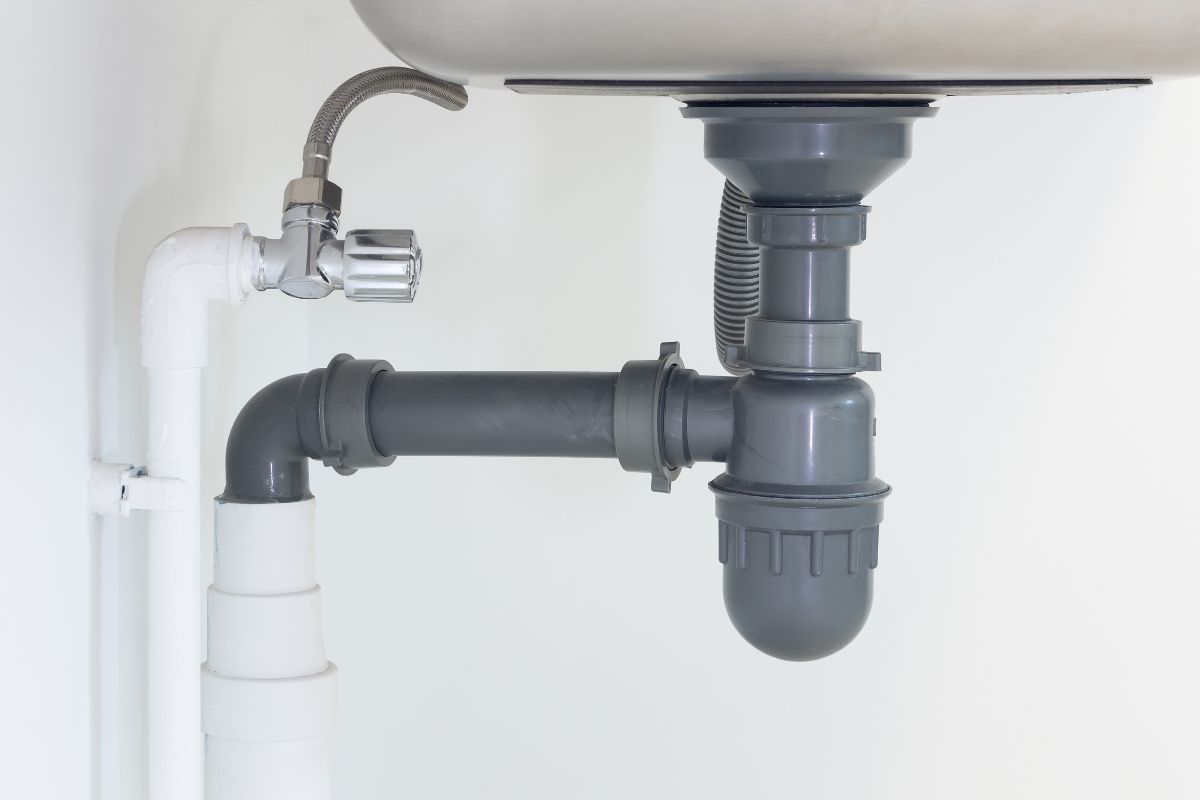 厨房水槽下排水管或下水道。bd手机下载Pvc塑料管和灵活的供应管连接不锈钢水槽包括水龙头,废水和废物的陷阱在排水和管道系统。