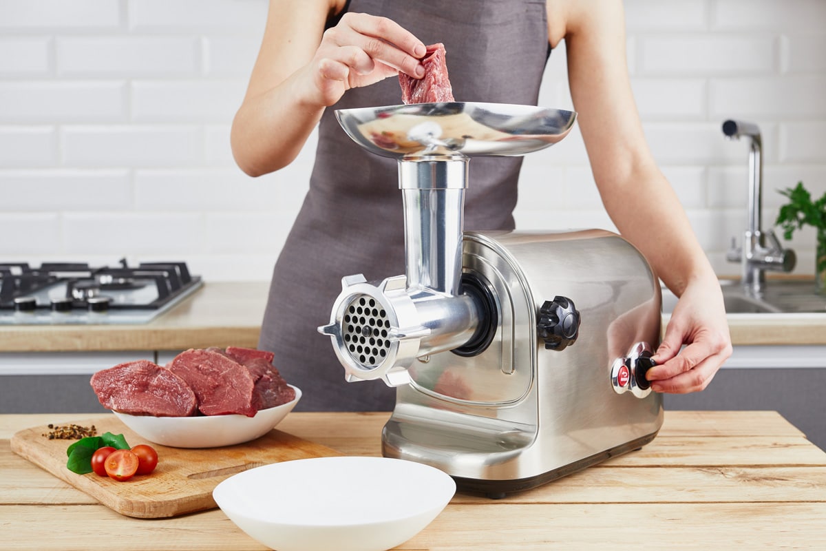 准备的过程五香碎肉的绞肉机。女性的手在厨房使用绞肉机。bd手机下载